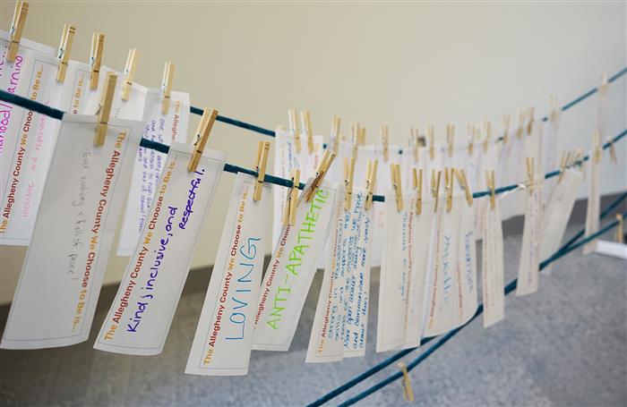 A clothesline featuring pinned pieces of paper that describe what attendees want Allegheny County to be.